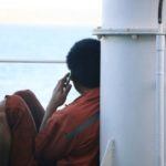 Seafarer sitting aboard, calling his family
