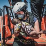 A Rescuer with a baby in her hands onboard