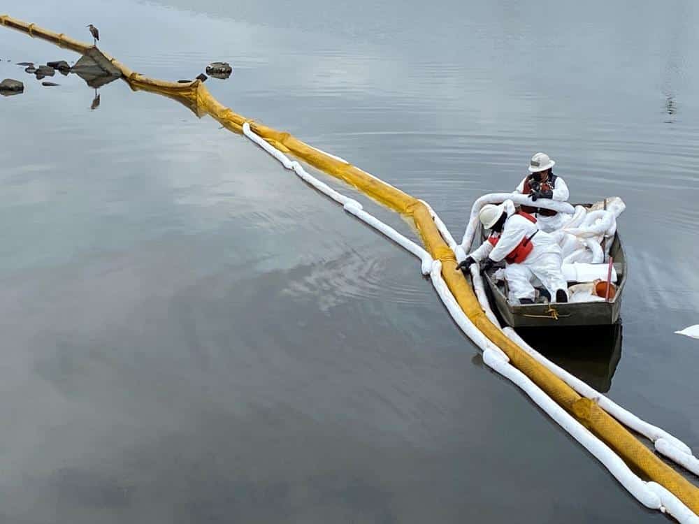 Contractors remove oil near a marsh area in Huntington Beach, California