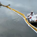 Contractors remove oil near a marsh area in Huntington Beach, California
