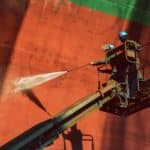 Two woker Washing or cleaning by high pressure water jet. Cargo ship external wall cleaning shell are doing these people at shipyard in Thailand on retro filter tone.