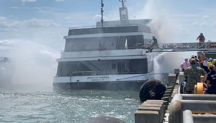 Firefighters boarding the Spirit of Norfolk during firefighting efforts.